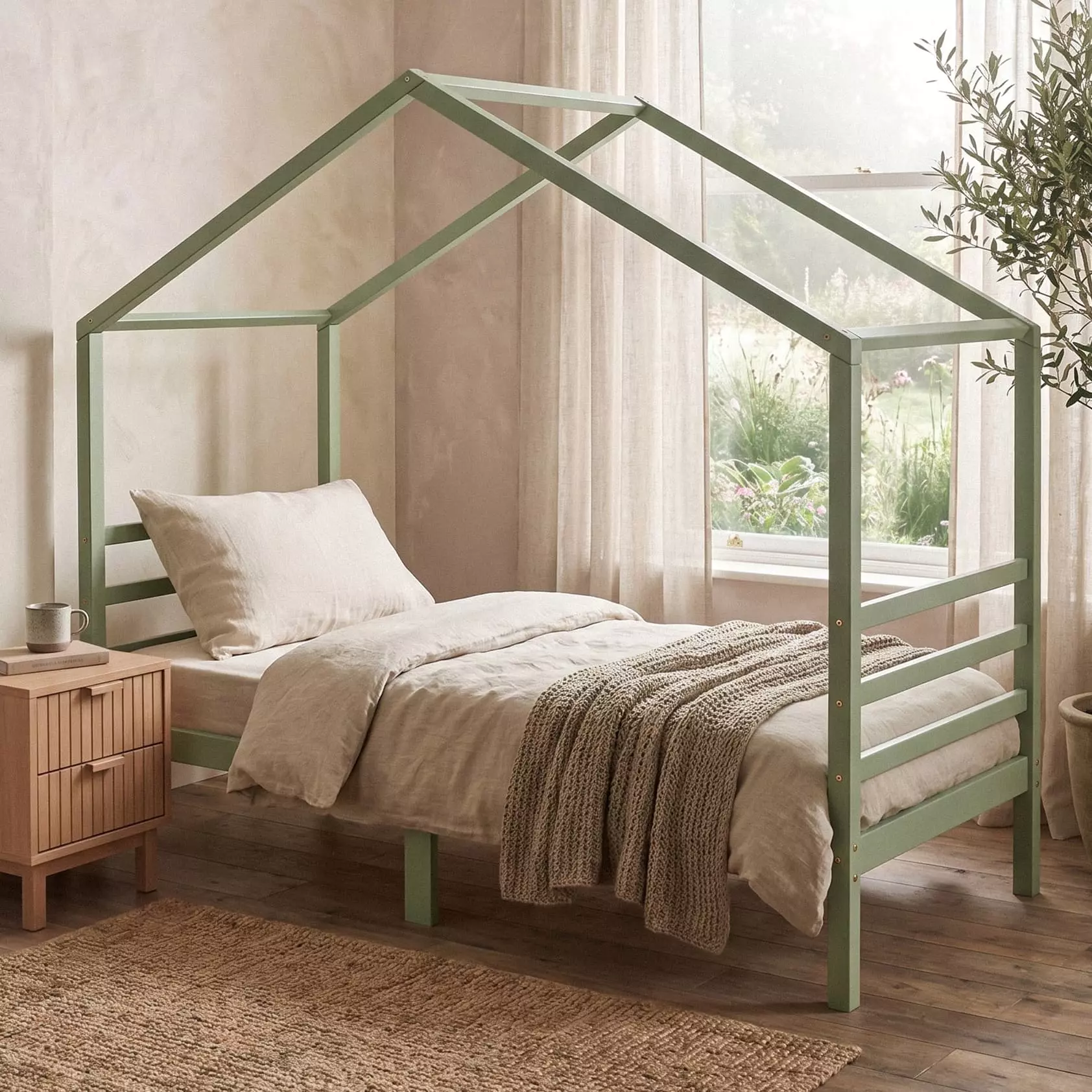 Kinderbett in Salbeigrün als Hausbett 90x200 im ruhigen Zimmer mit Leinenbettwäsche, Jute-Teppich und Olivenbaum am Fenster